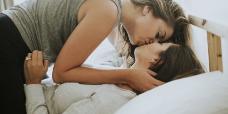 couple lesbien qui s'embrasse au lit en pratiquant le slow sex